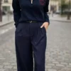 Pull femme bleu marine Los Angeles à col montant zippé avec inscription rouge sur la poitrine, porté avec un pantalon large bleu marine.