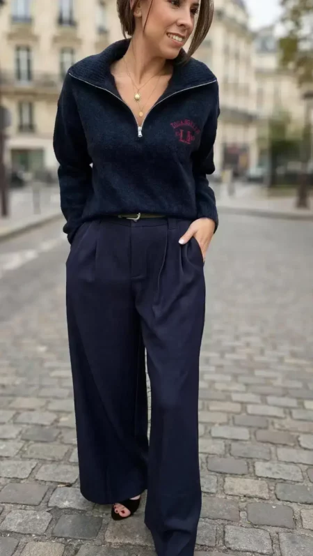 Pull femme bleu marine Los Angeles à col montant zippé avec inscription rouge sur la poitrine, porté avec un pantalon large bleu marine.