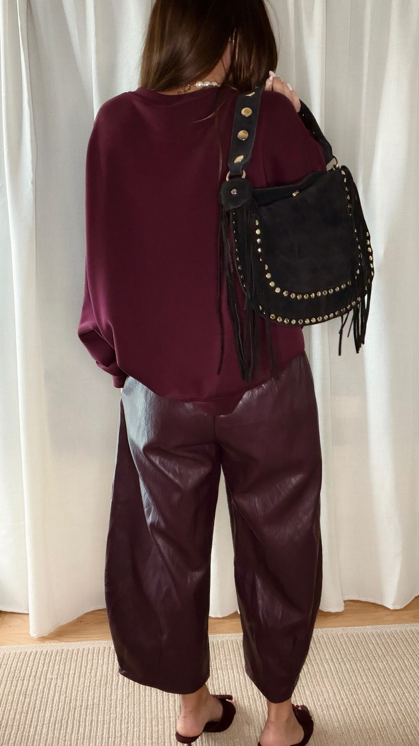 Sac noir femme à franges avec clous dorés, porté à l’épaule, style bohème chic