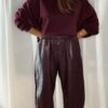 Sweat bordeaux femme porté avec un pantalon marron fluide et un sac à franges, tenue chic et tendance