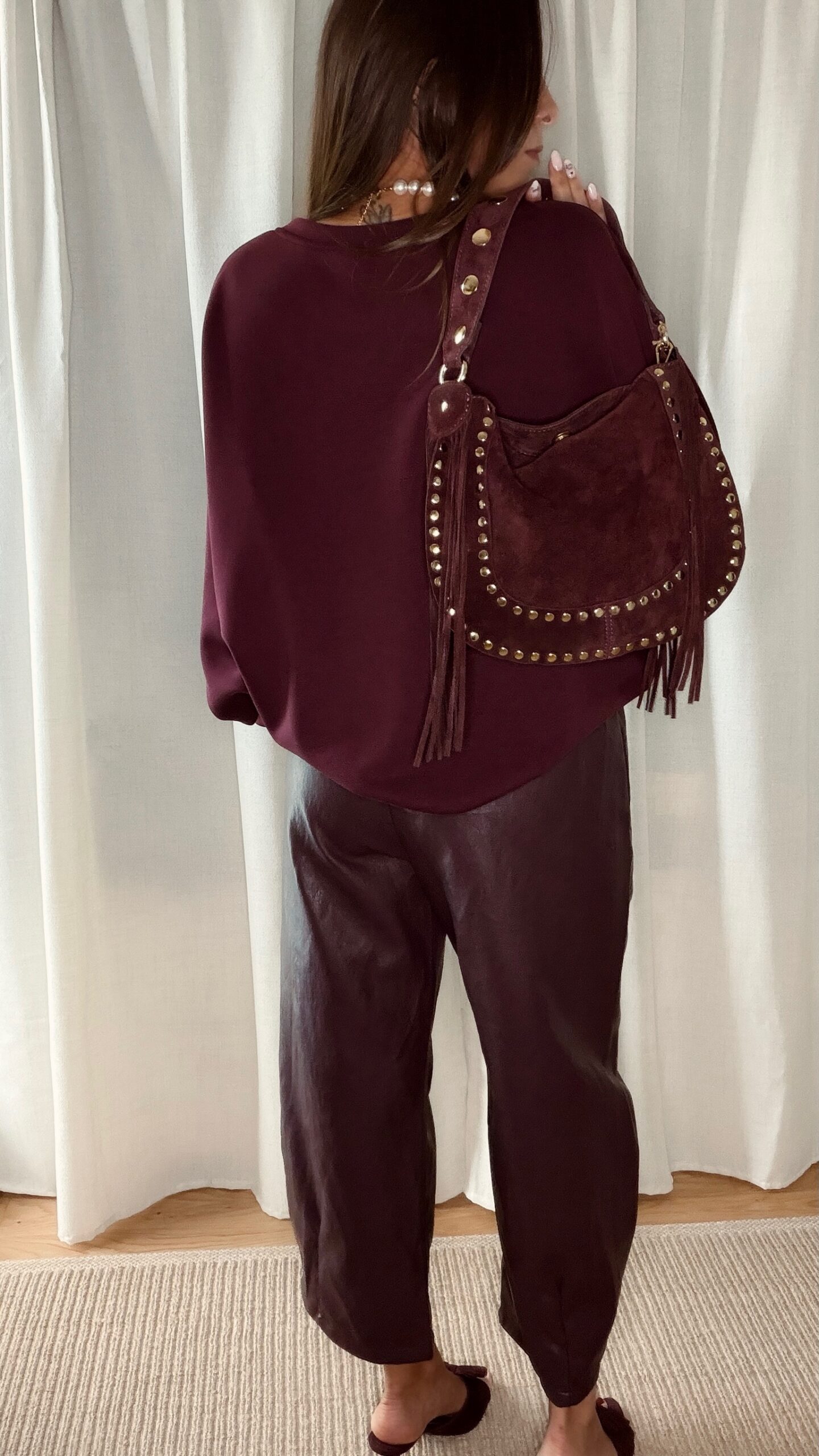 Sac bordeaux femme à franges avec clous dorés, porté à l’épaule, style bohème chic