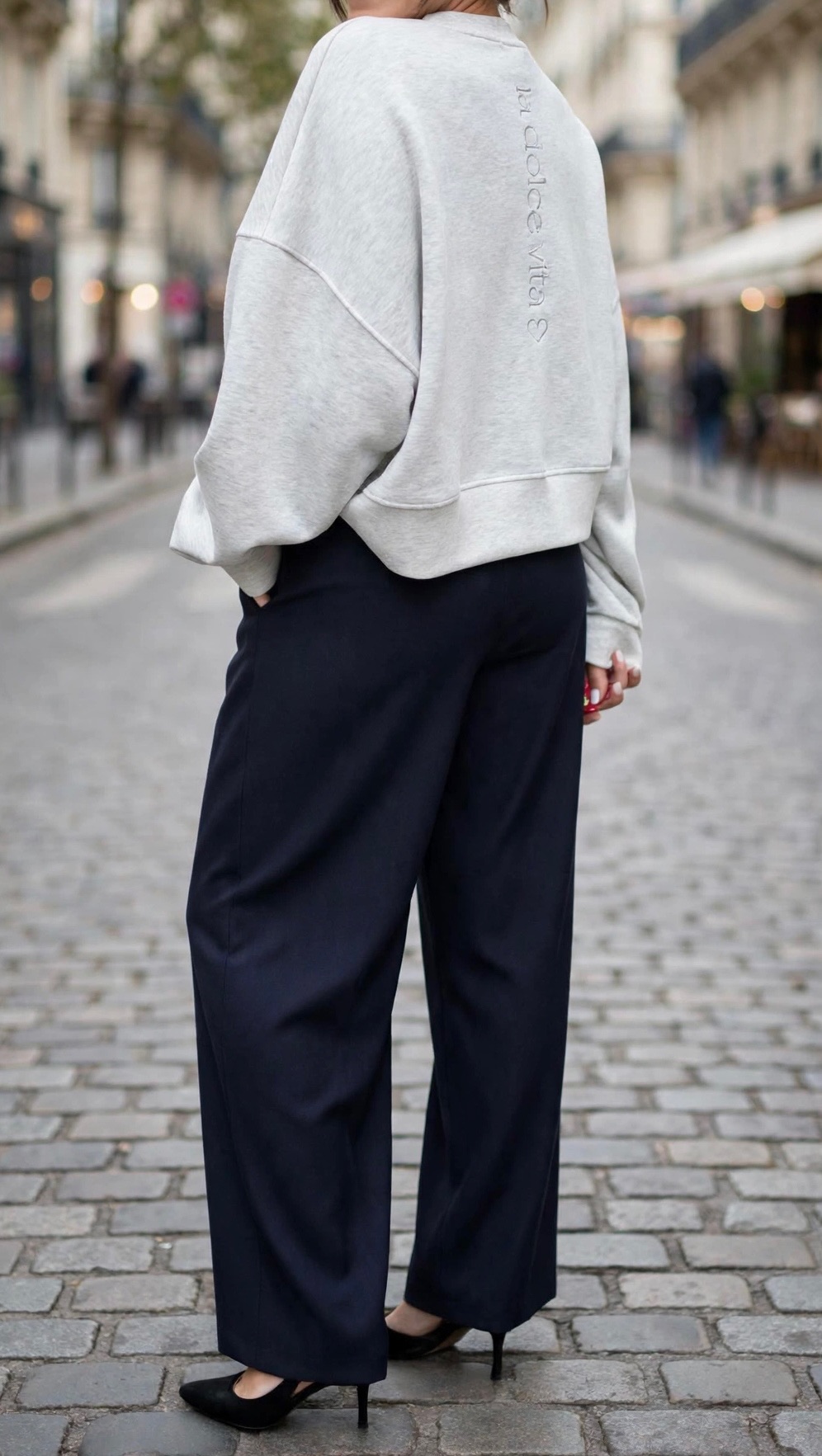 Femme portant un sweatshirt gris clair oversize et un pantalon large bleu marine taille haute, une tenue chic et décontractée pour femme.